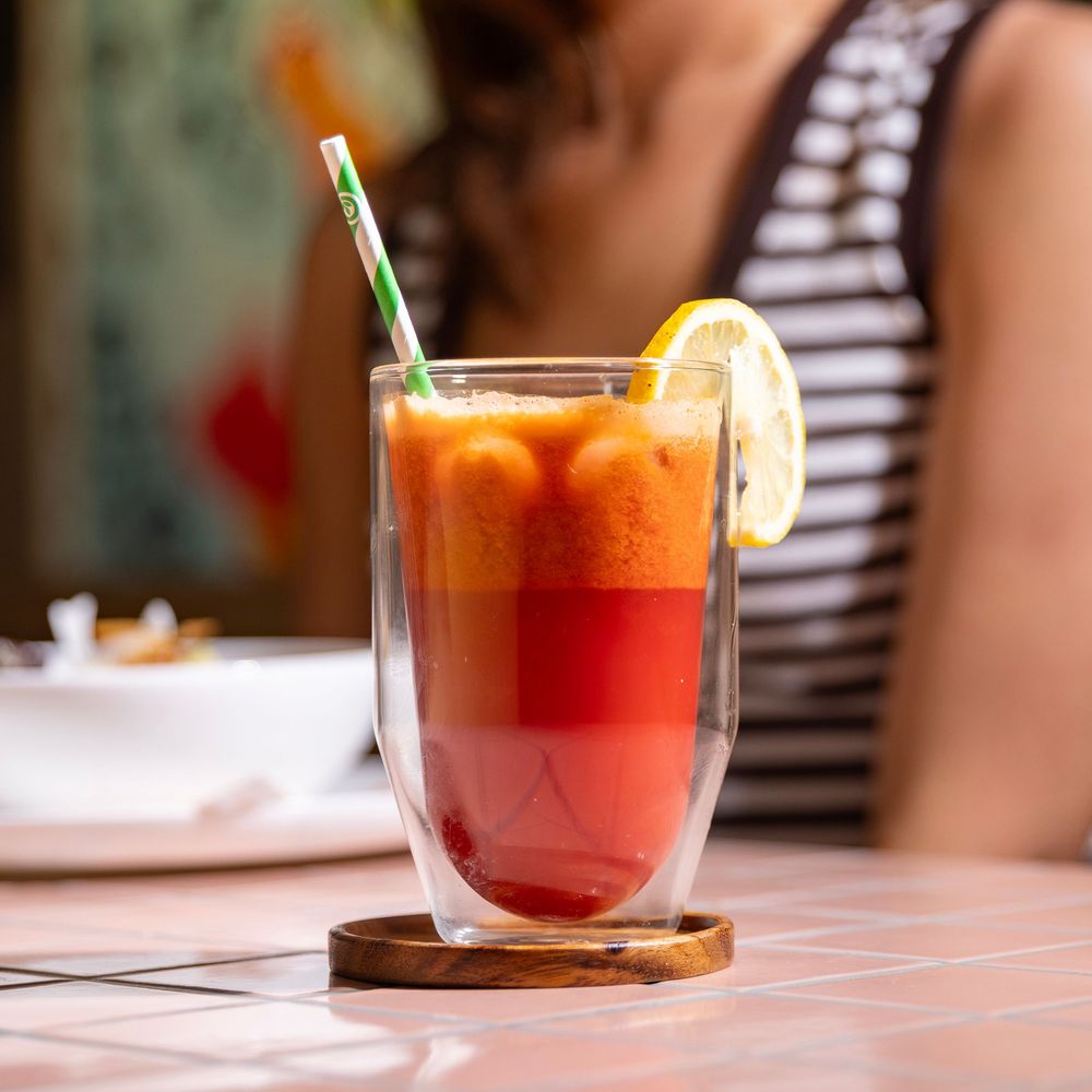 red smoothie sitting on a pink background with a person in the background