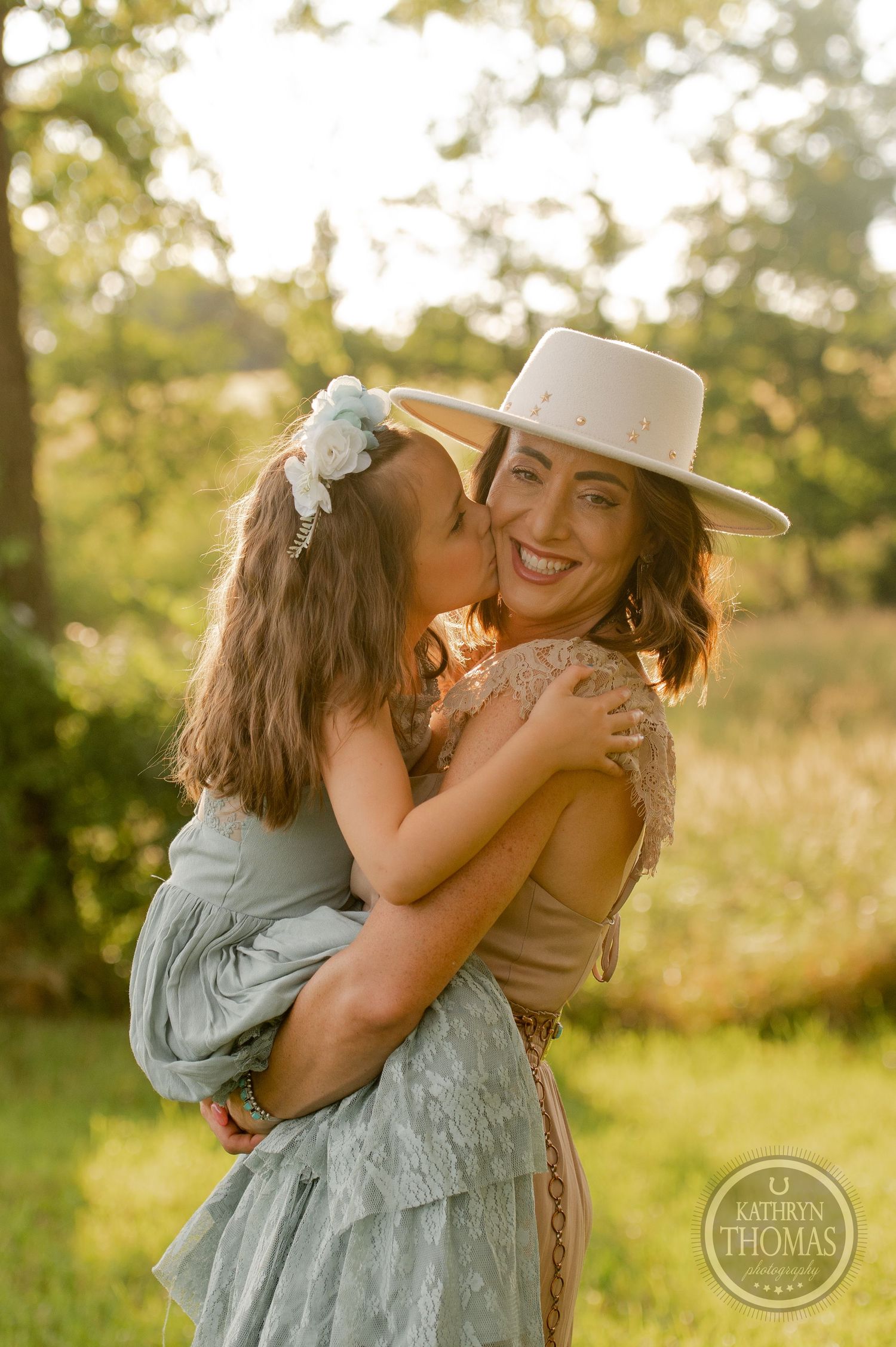 Sweet moment shared in warm evening sunlight with coordinated outfits in sage and neutral tones.