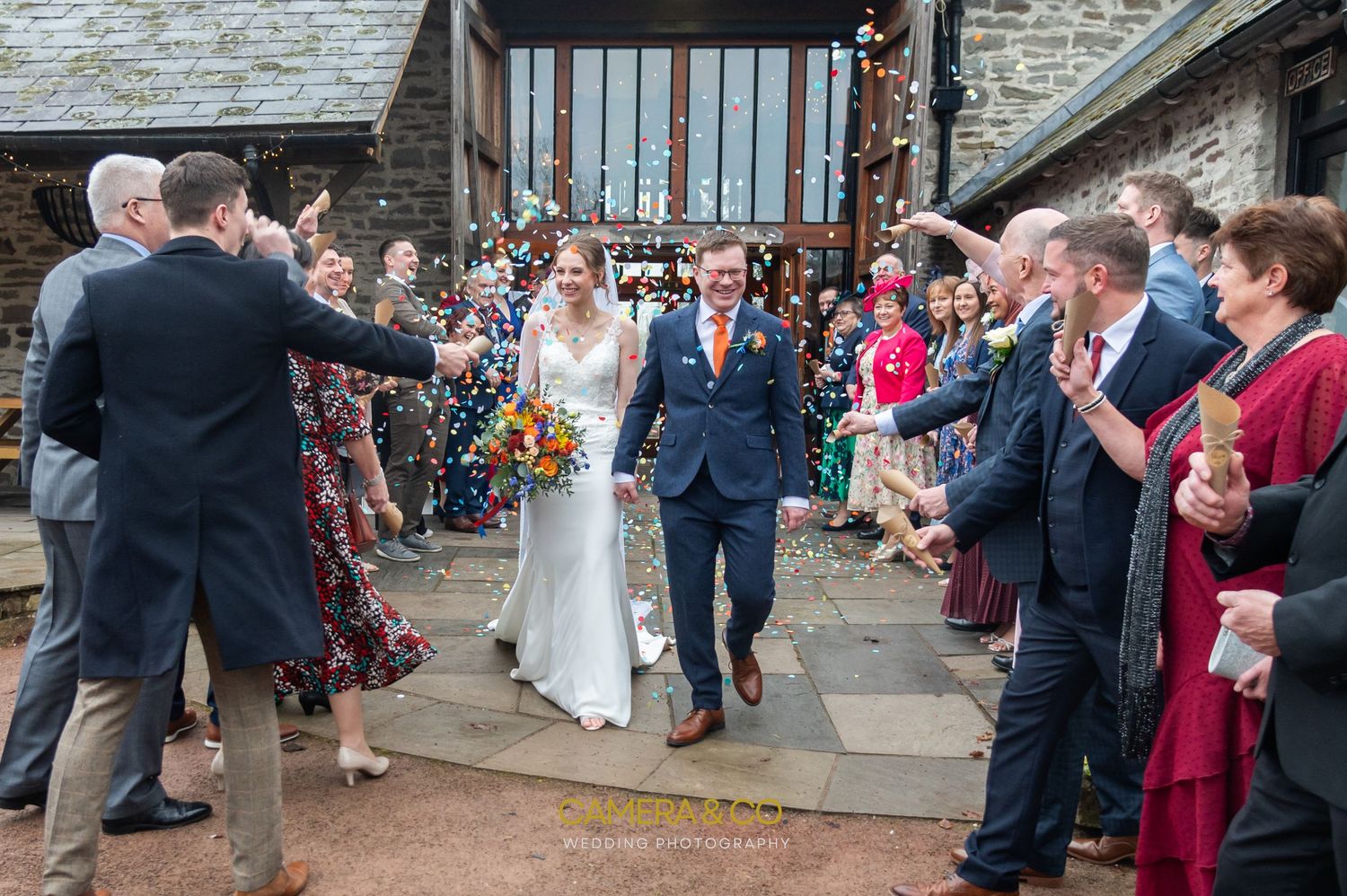 Wedding guests celebrating outside a stone building during a reception.