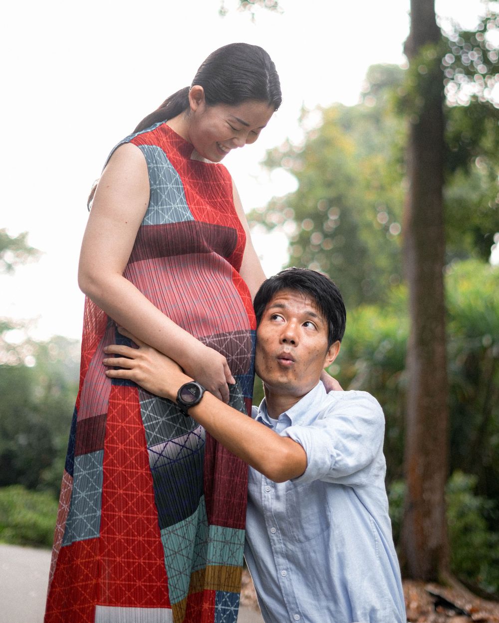 A playful maternity photoshoot featuring a pregnant woman in a patterned red dress.