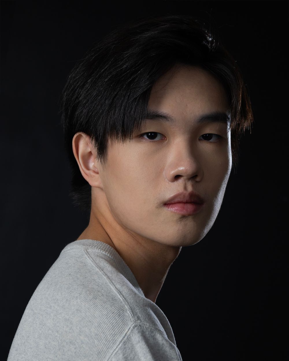 Dramatic side profile portrait against black background with dramatic lighting.