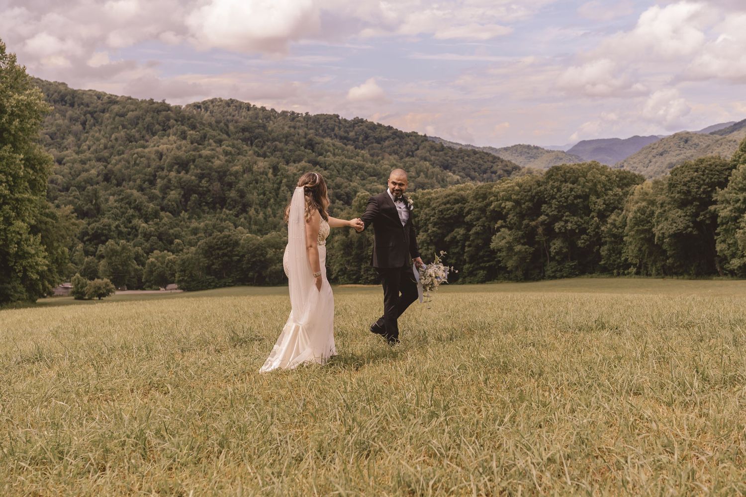 Bride and groom walking with mountain views at The Heavens Venue in Hot Springs, NC