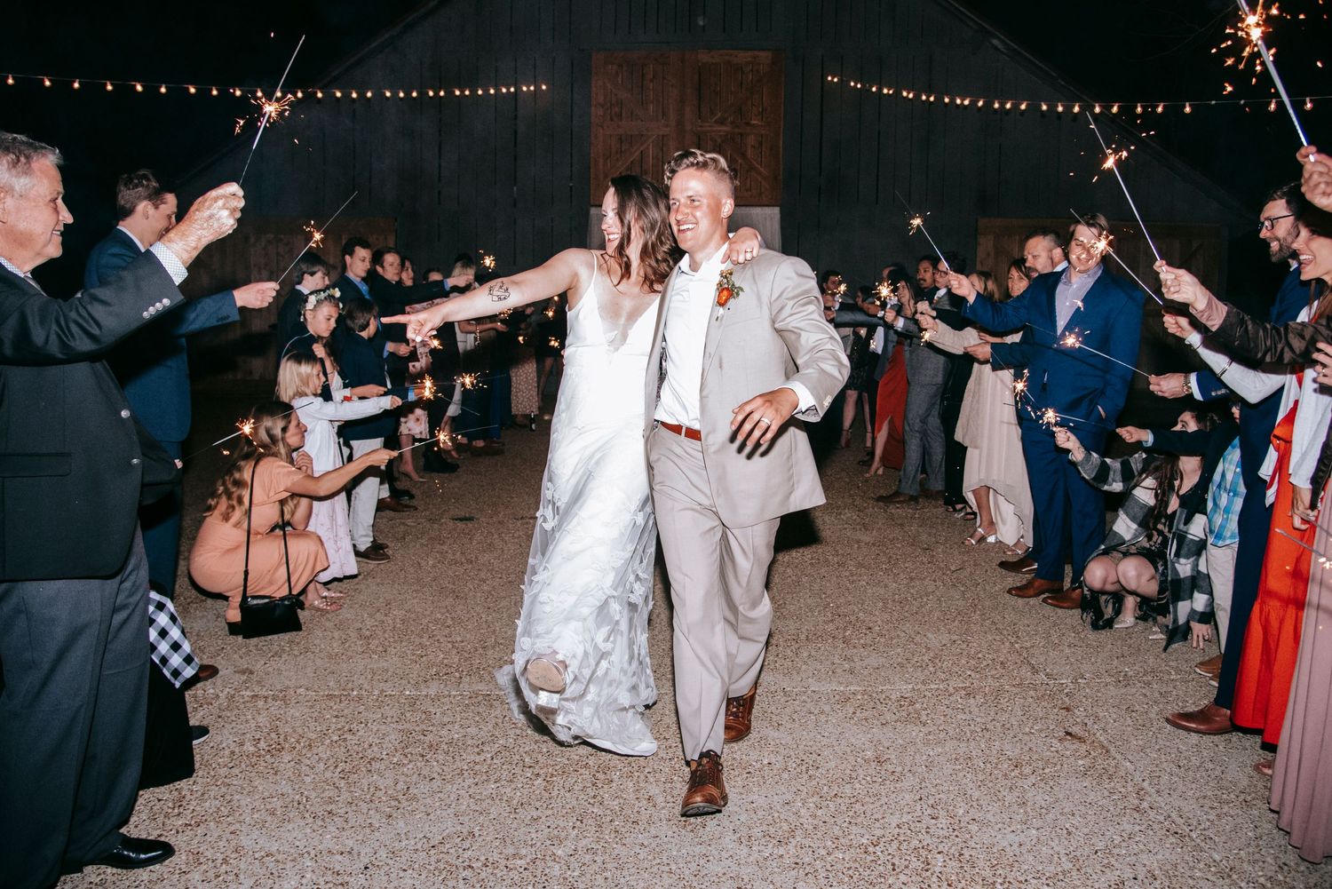 Newlyweds make their grand exit through a sparkler tunnel at their wedding reception.