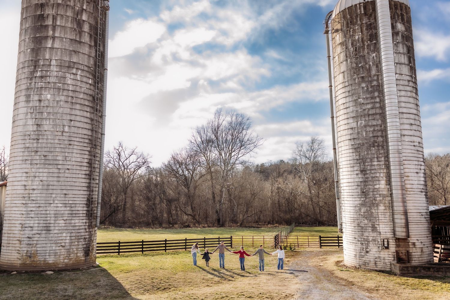 Tall concrete farm silos stand against blue cloudy sky with small exercise equipment visible at their base.