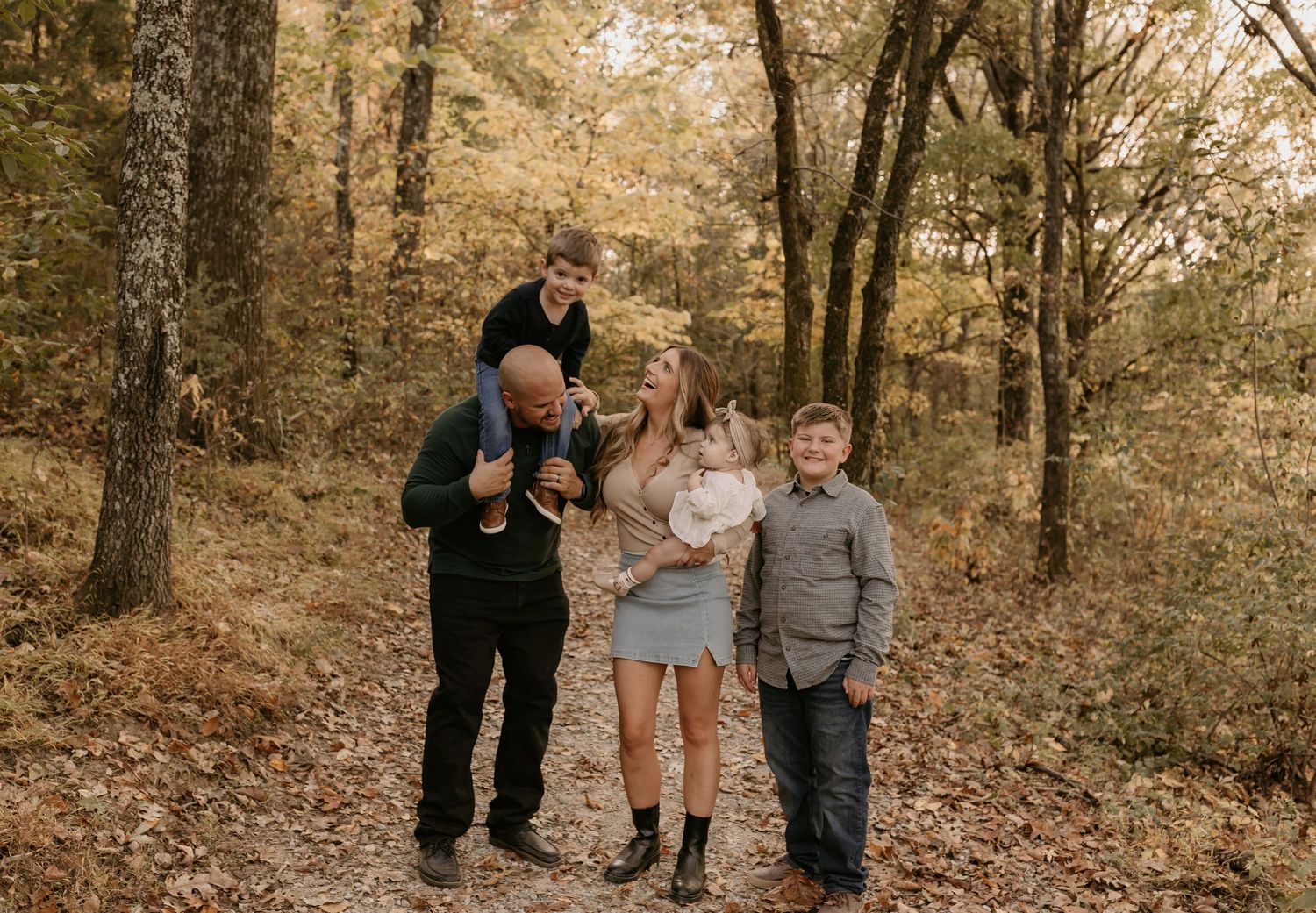 A family walking together through autumn woods during a fall photoshoot.