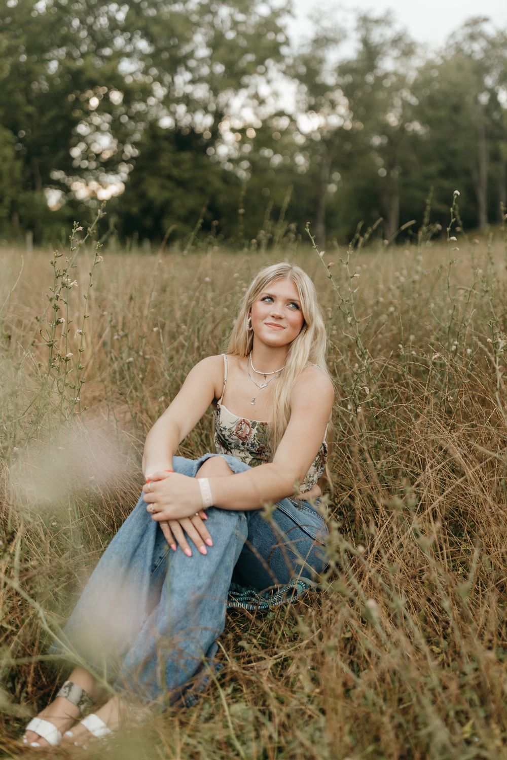 Artistic outdoor portrait taken in a tall grass meadow during golden hour with bokeh lighting effects. Virginia graduation/senior session.