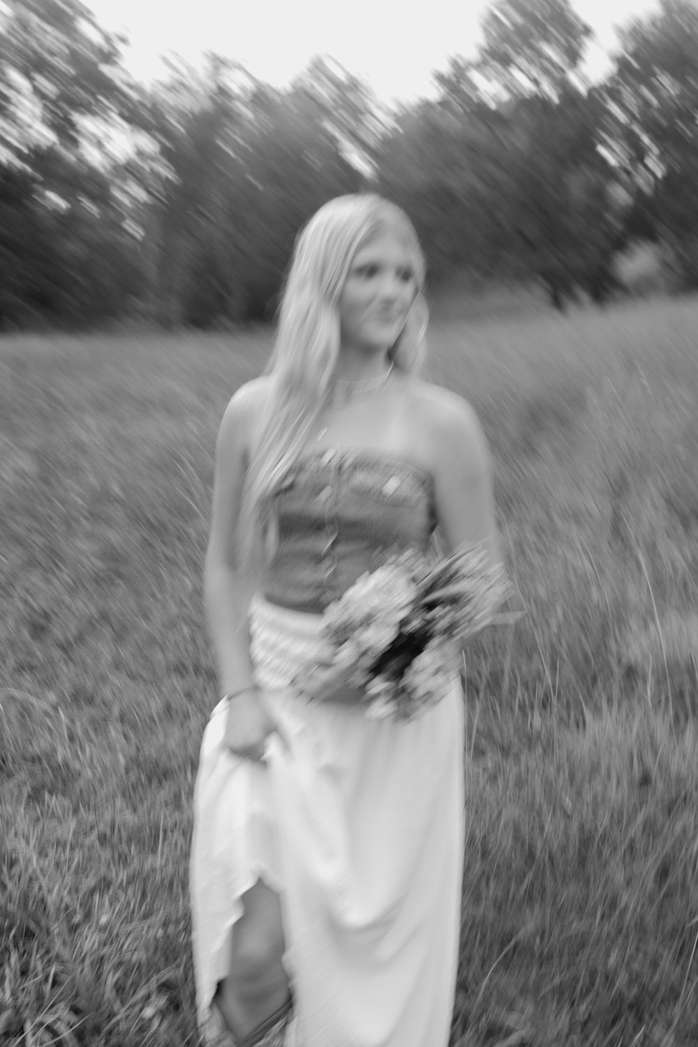 Black and white portrait photograph with dreamy motion blur effect in a natural outdoor setting. Virginia graduation/senior session.