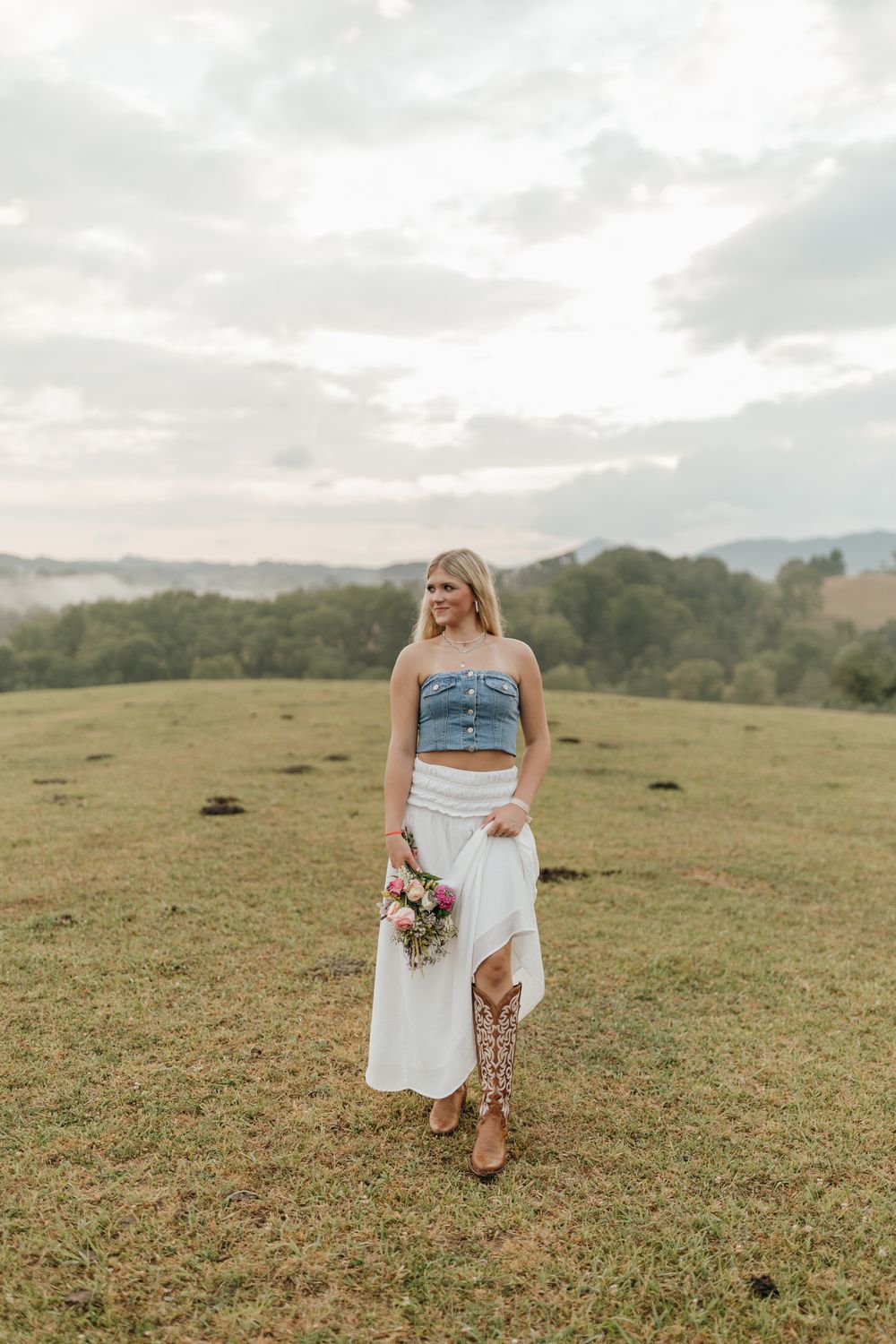 Stylish summer outfit featuring a denim crop top and white skirt in a rolling countryside setting. Virginia graduation/senior session.