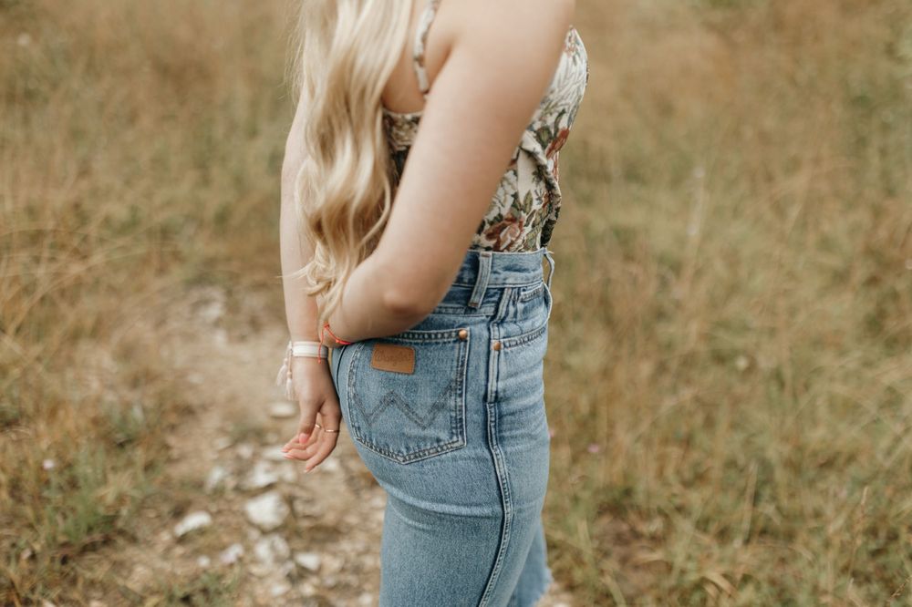 Close-up detail of denim crop top with classic jean pocket stitching against rustic outdoor background. Virginia graduation/senior session.