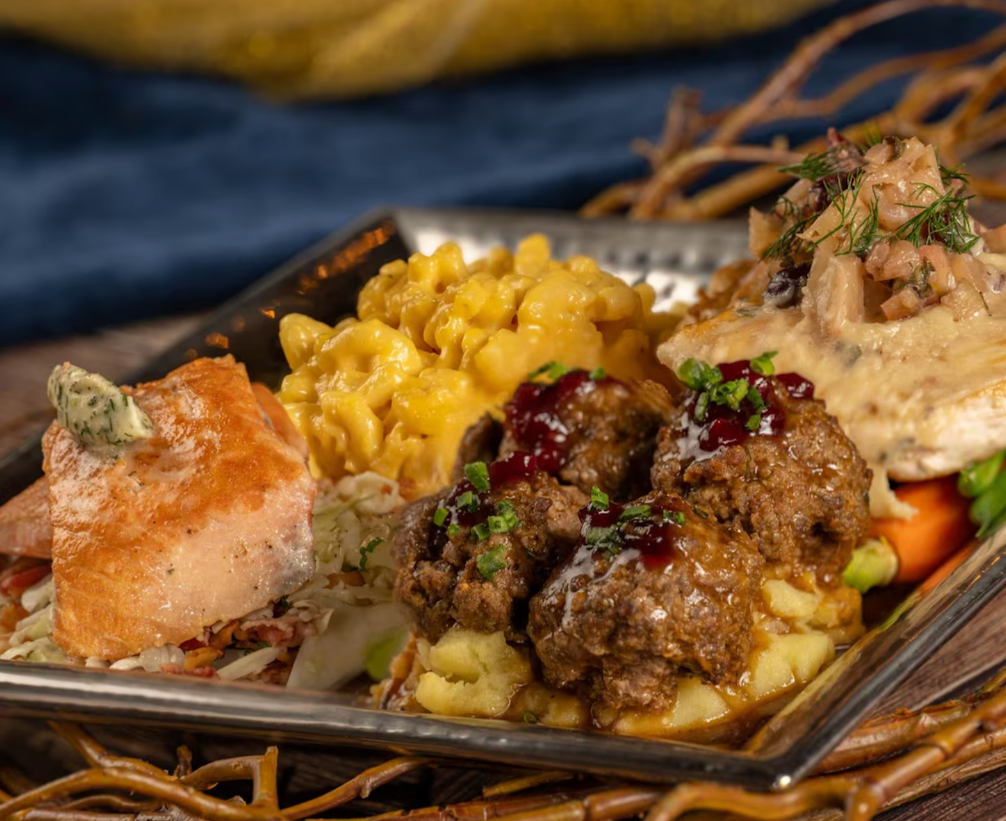 Gourmet dinner plate featuring meat, macaroni and cheese, and vegetables with garnish.