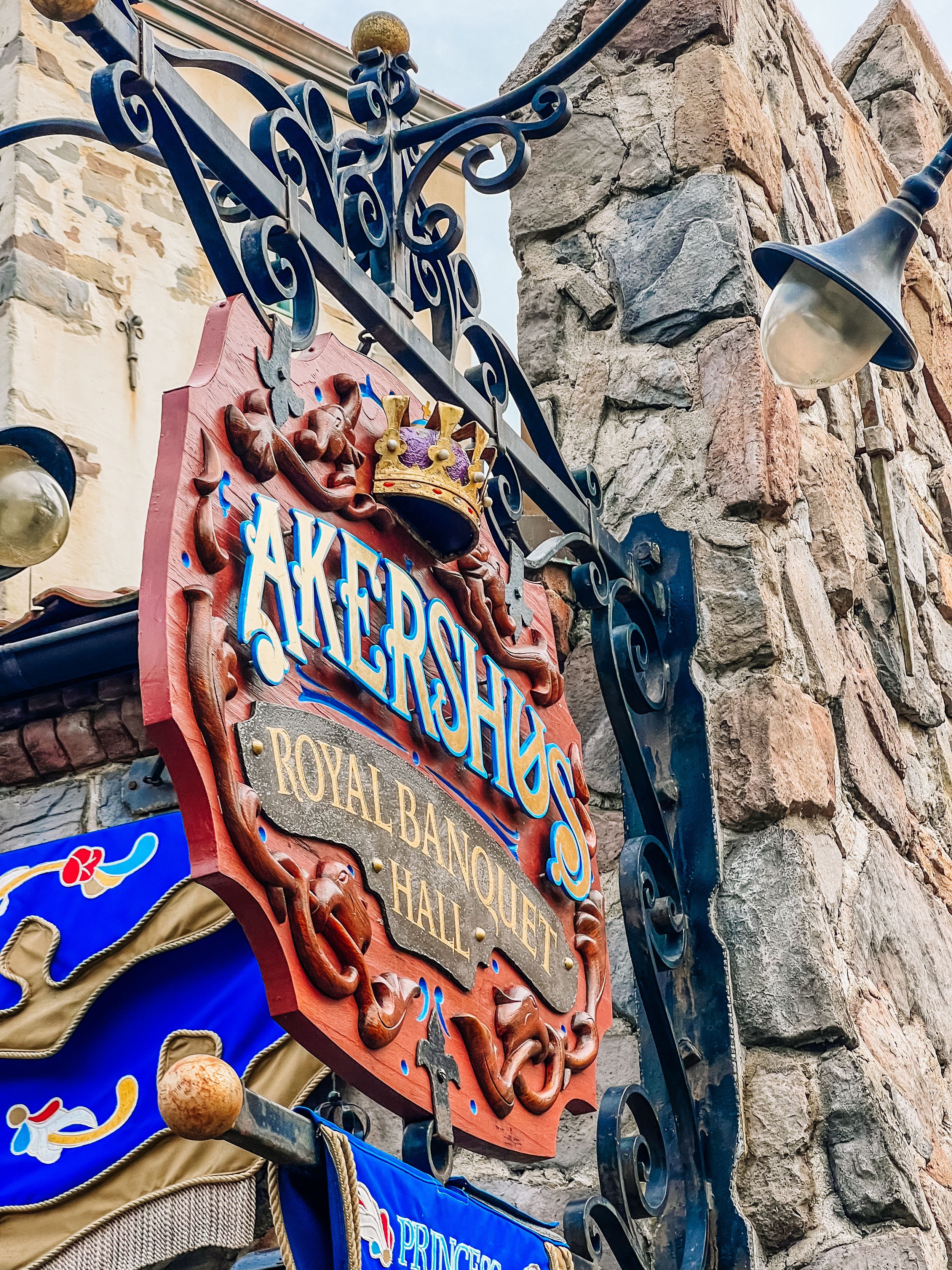Ornate vintage-style sign with decorative metalwork mounted on stone wall.