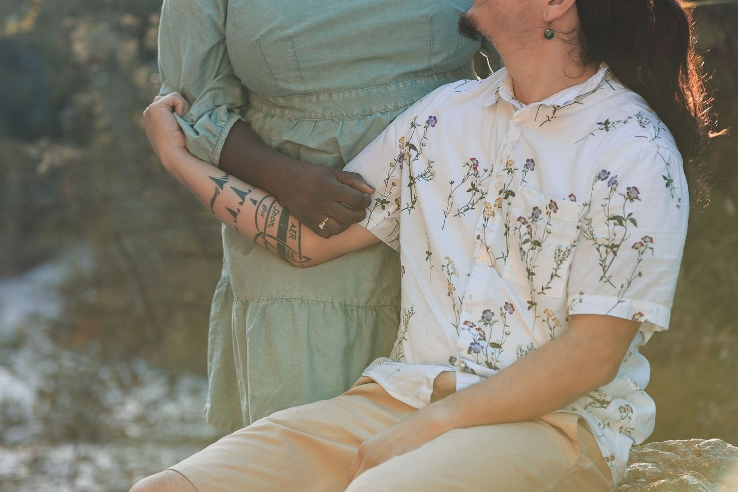 A group in sage green and floral outfits sits together outdoors during golden hour lighting.