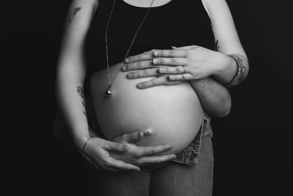 A black and white photo series showing various intimate close-up shots of a pregnant woman's belly.