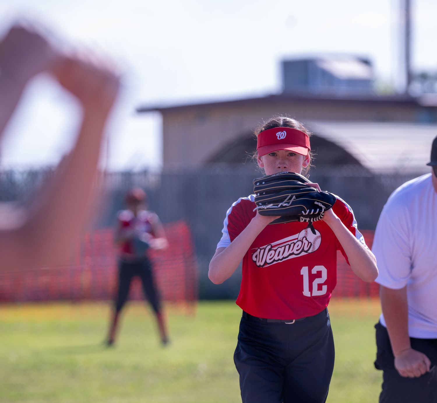 Softball pitcher in red uniform practicing throwing mechanics.