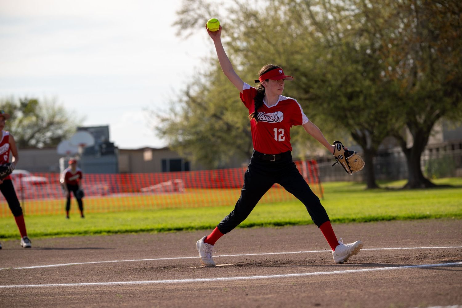 Players positioned strategically across softball diamond during competitive game.
