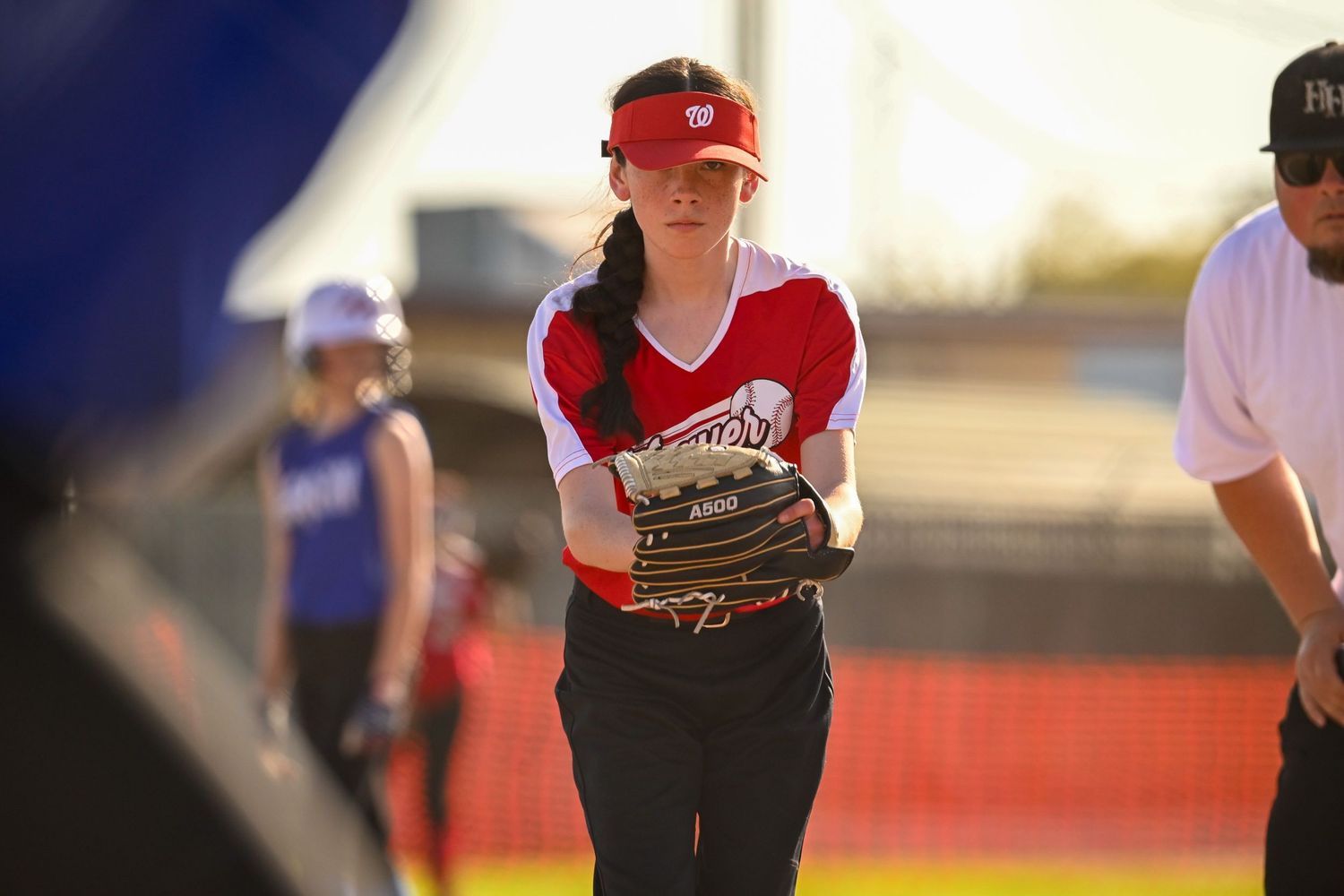 Players in red and white uniforms spread across softball field during afternoon game.