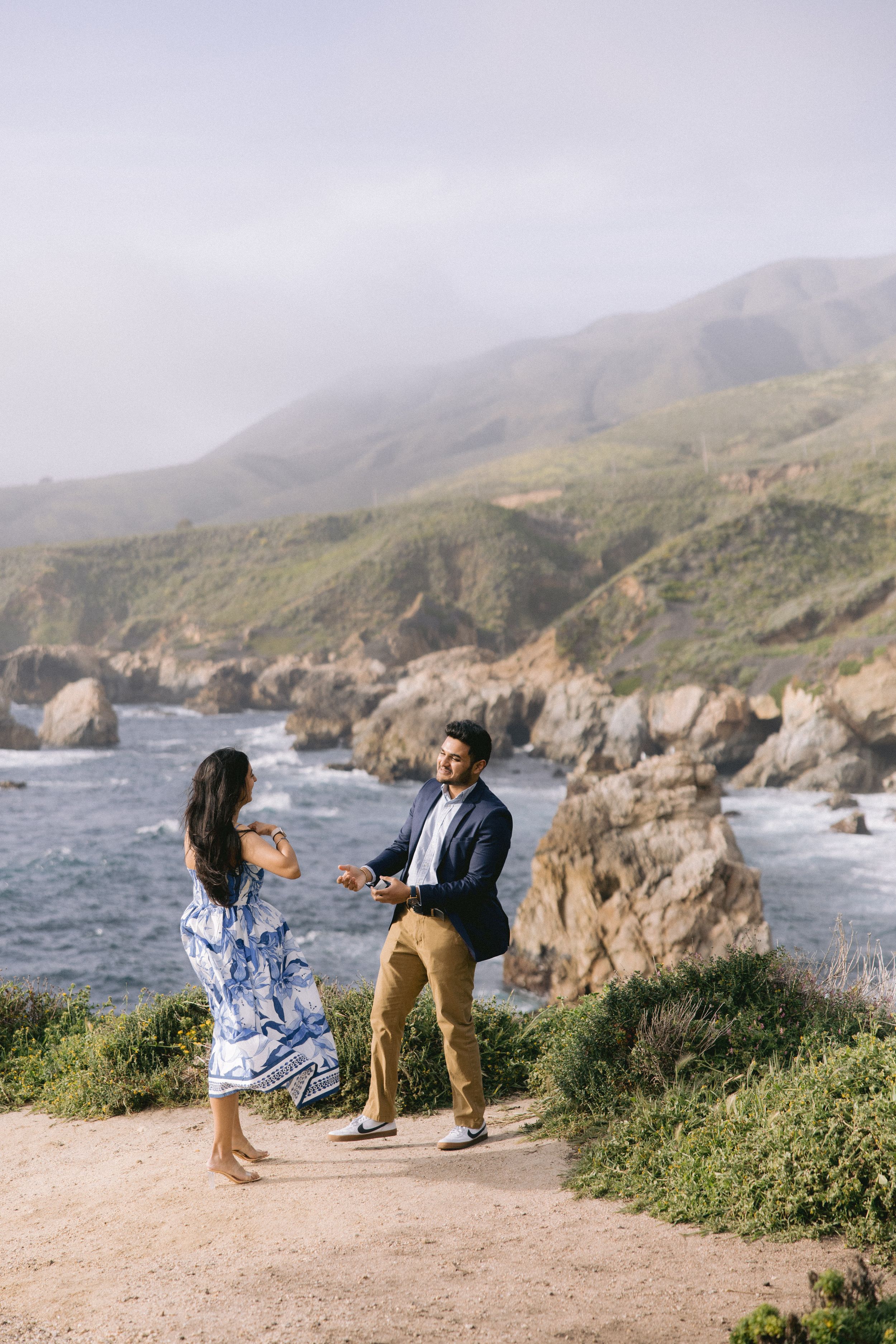 Couple enjoying a romantic moment on a scenic overlook above the dramatic Big Sur coastline in California.