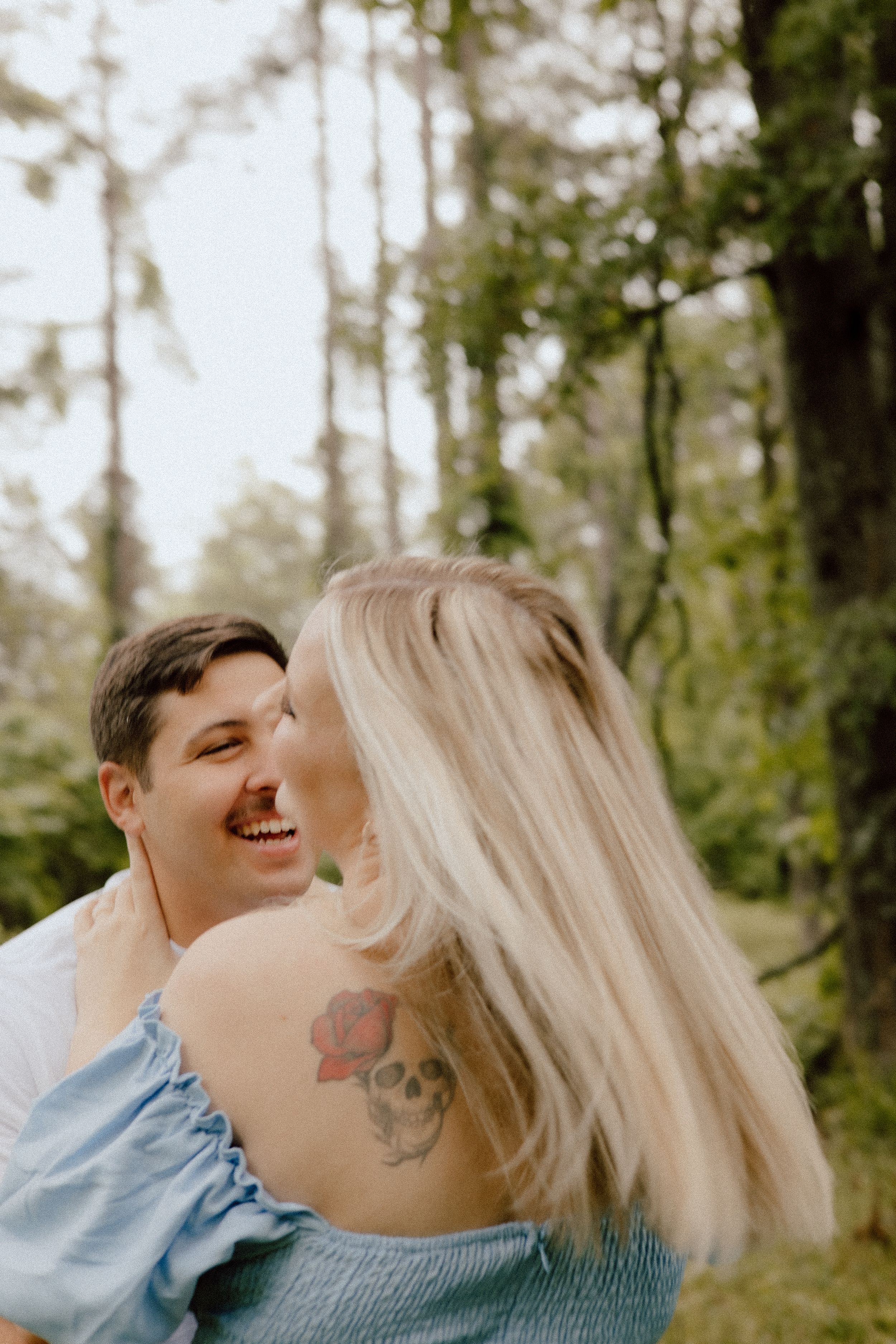 A joyful intimate moment shared between a couple in a wooded outdoor setting.