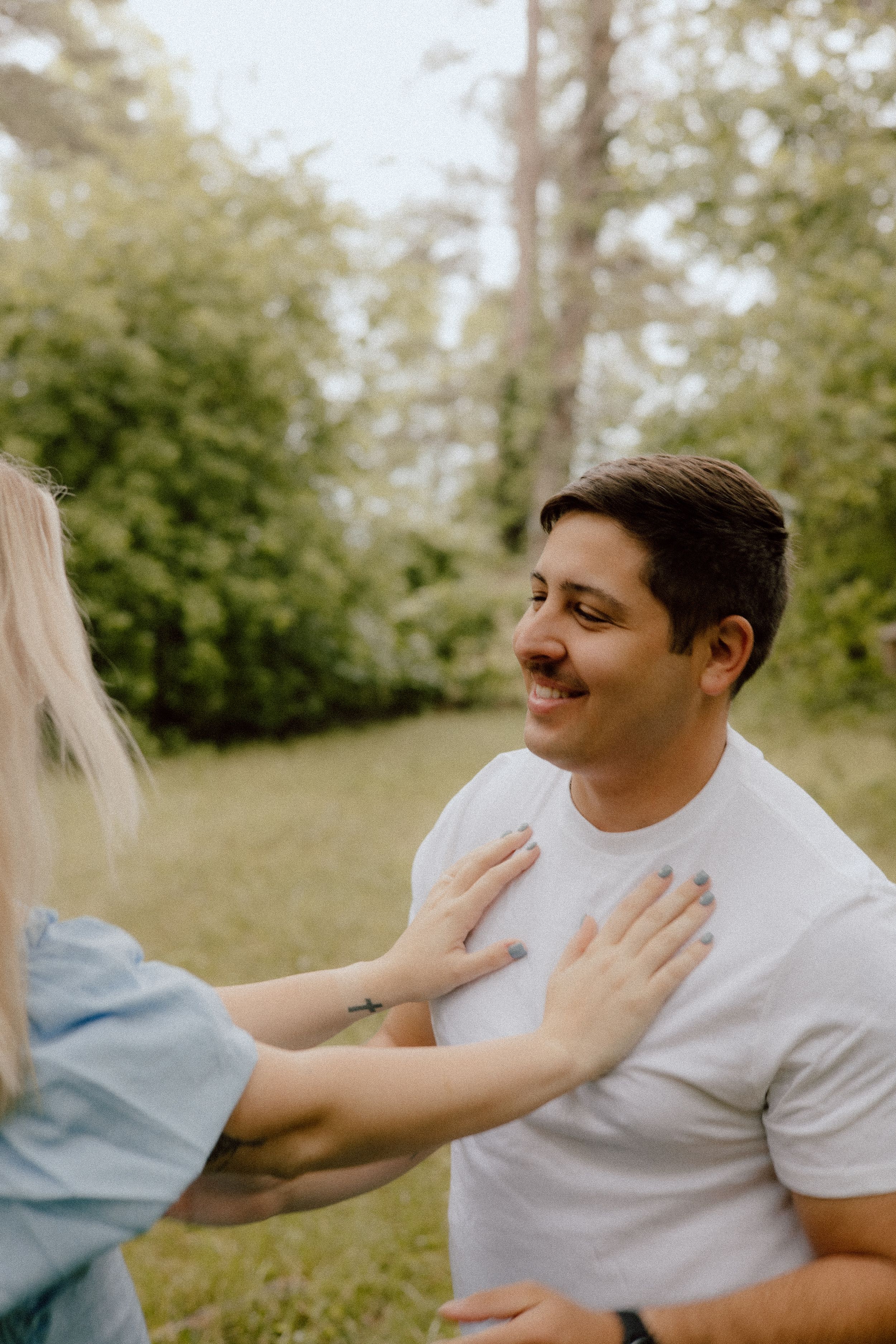 A tender moment between two people in a garden setting, with hands reaching out in a gentle gesture.