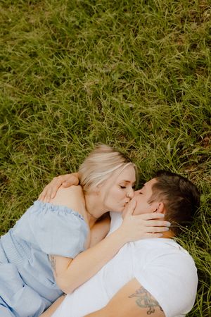 Intimate moment shared between two people lying in green grass on a sunny day.