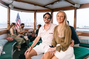 Guests relax on cushioned seating aboard a boat with an American flag visible in the background.