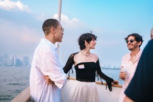 People enjoying drinks and conversation on a boat deck with city skyline in the background.