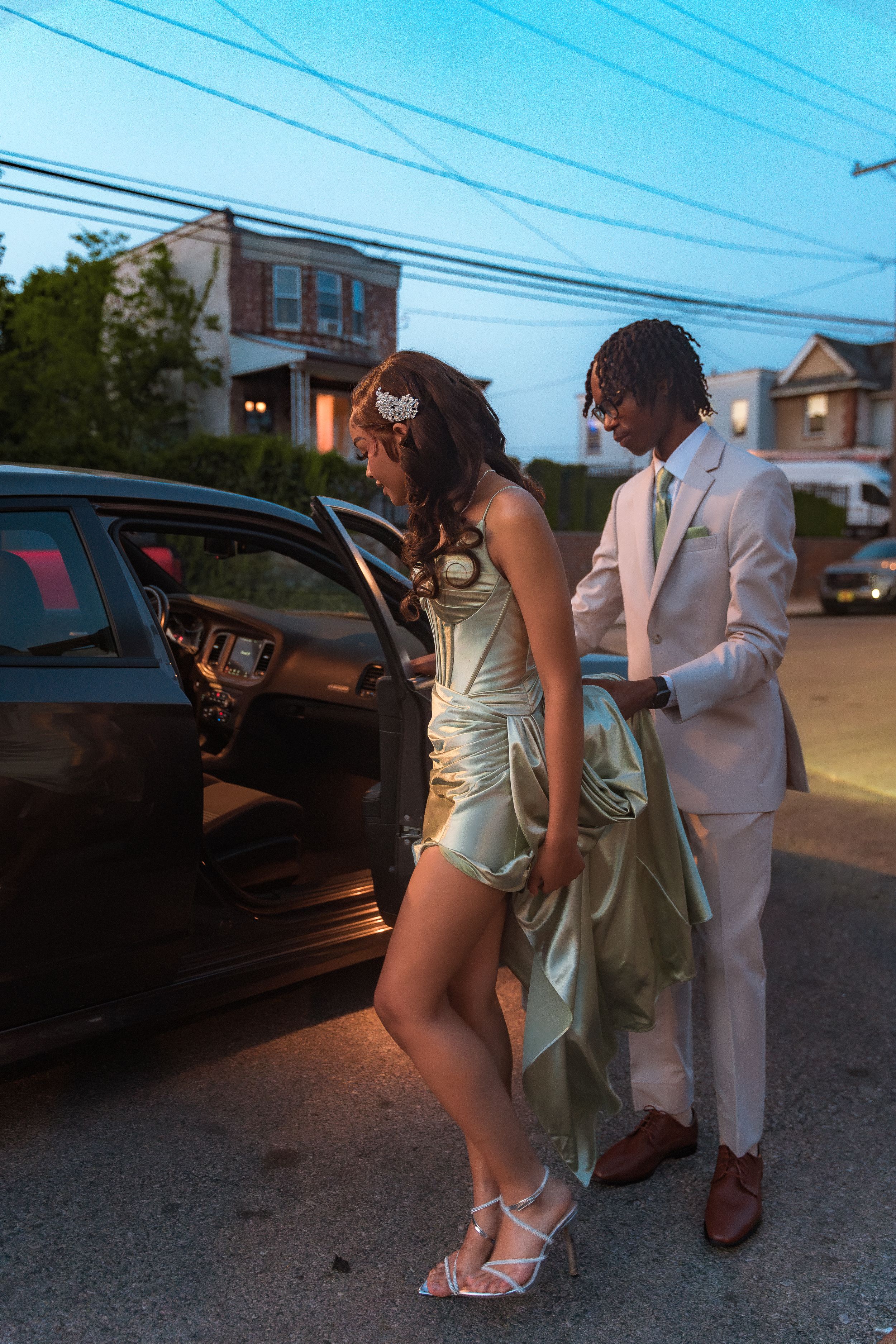 Formal couple getting into car during evening photoshoot.