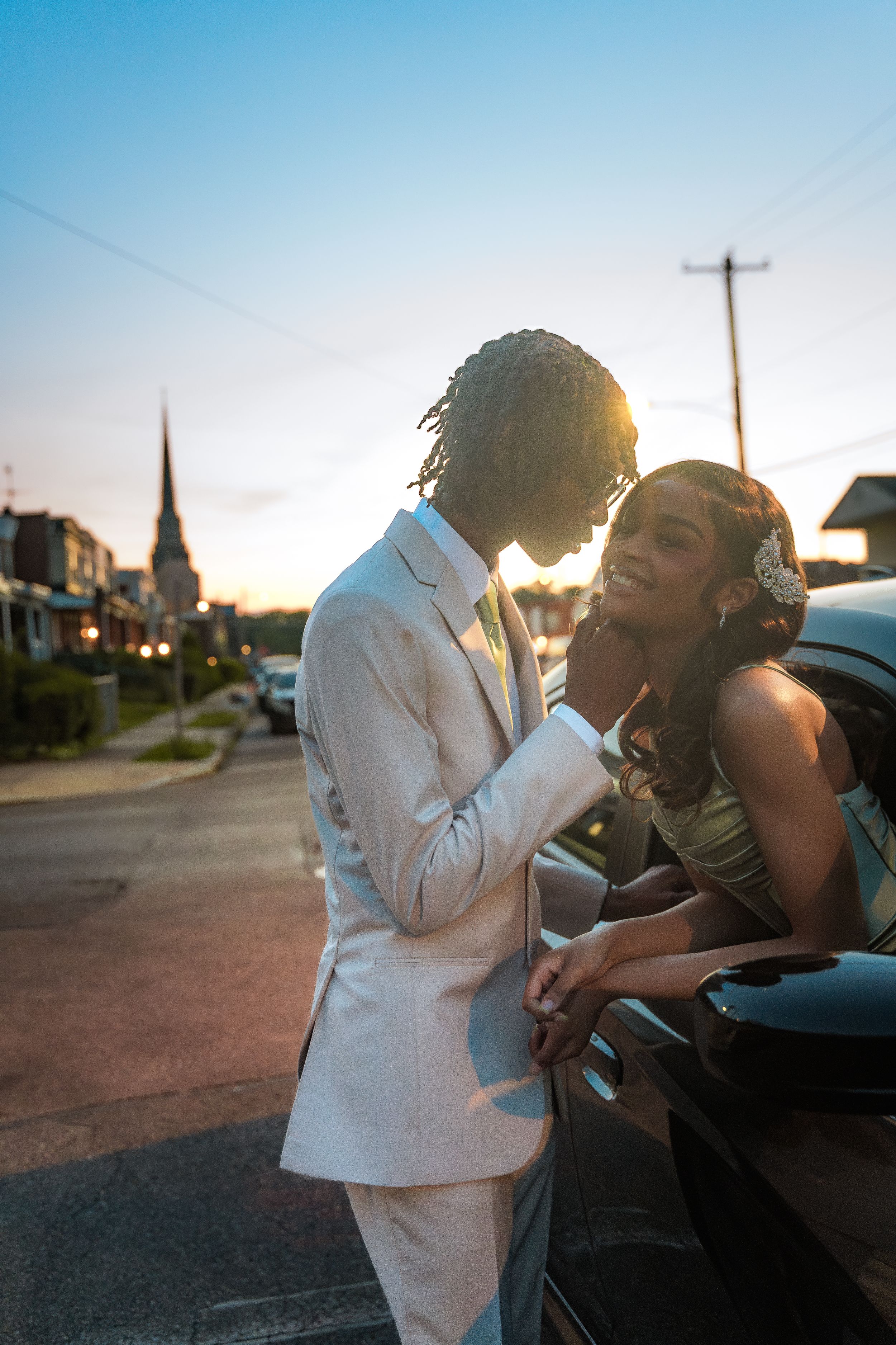 Romantic sunset portrait of couple in formal wear by car.