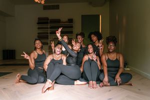 A group in matching gray activewear poses together during a yoga or fitness class.