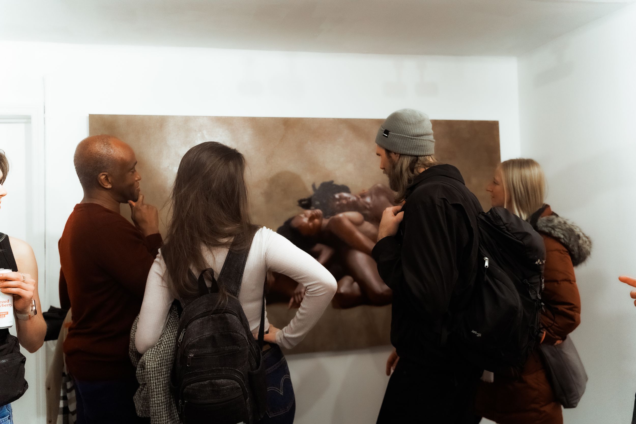 Group of people gathered around viewing artwork at a gallery exhibition.