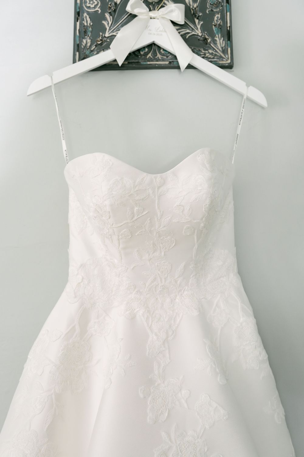 White lace wedding dress with sweetheart neckline displayed on elegant padded hanger.