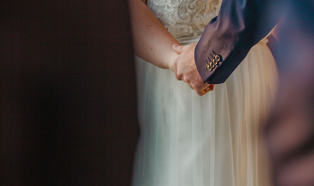A close-up shot of hands holding a Bible during a wedding ceremony.