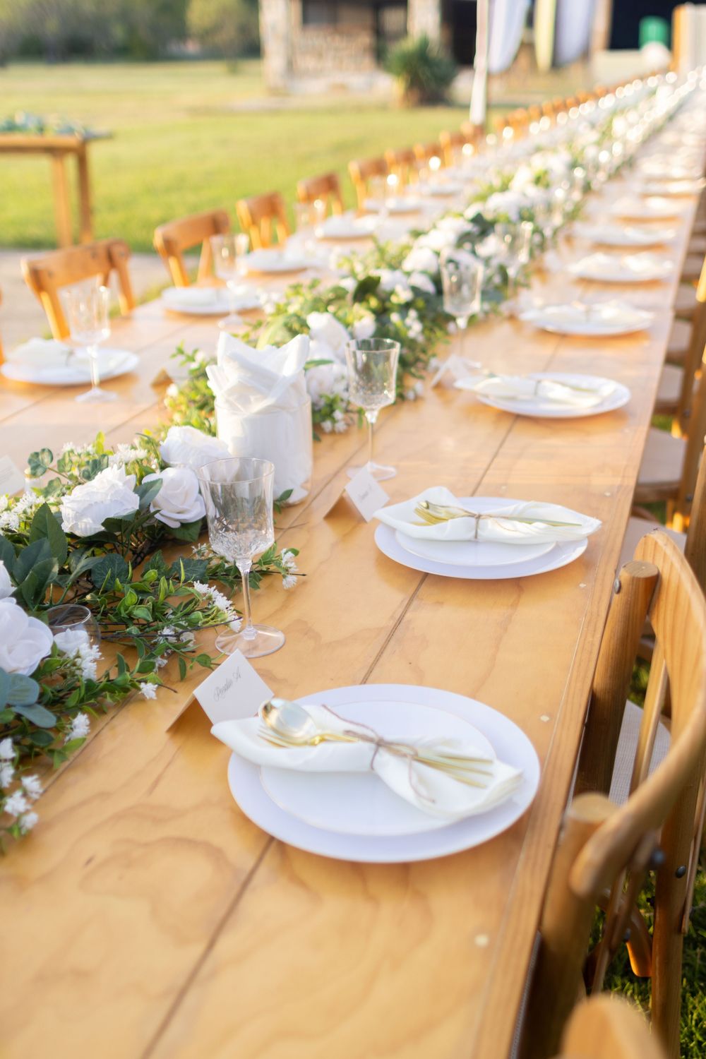 Elegant rustic wedding table setting with white floral centerpieces and natural wood tables.