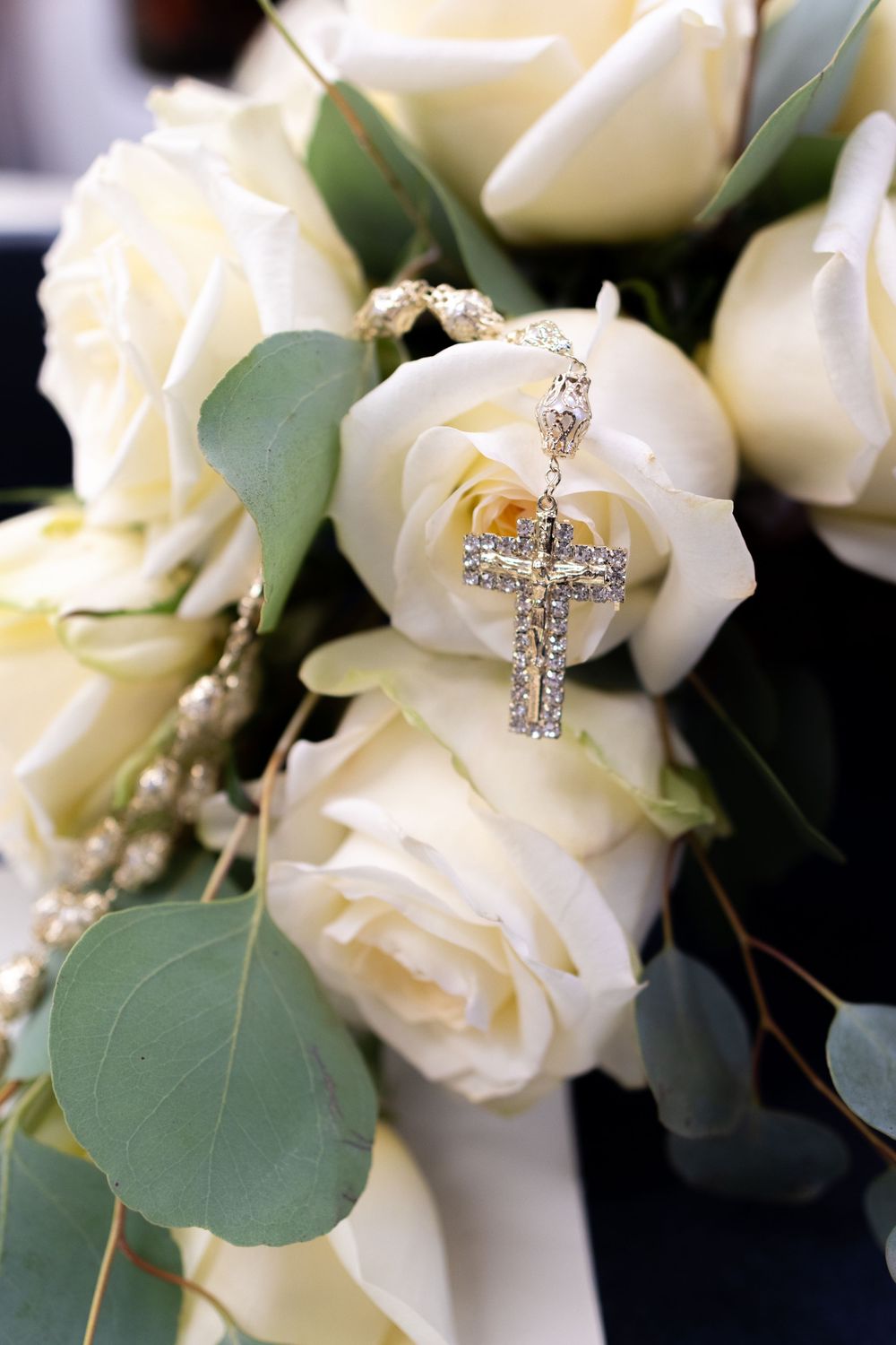 Delicate white roses with decorative silver key charms nestled among green leaves.