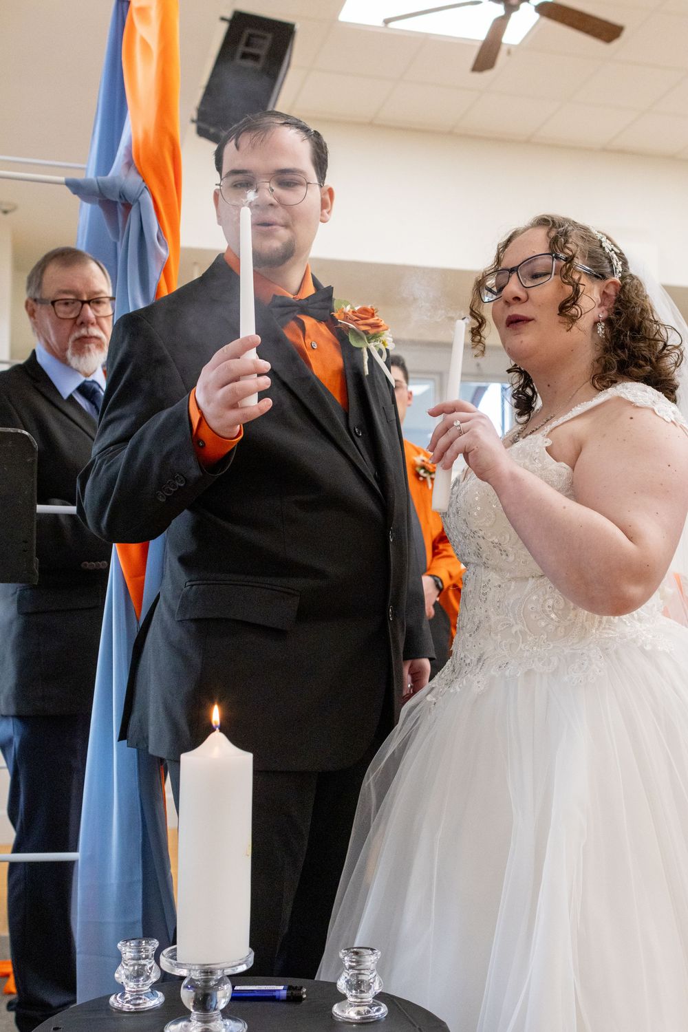 A couple in formal wedding attire lighting unity candles at The Landmark on Lee st in Greenville, TX  at their ceremony.