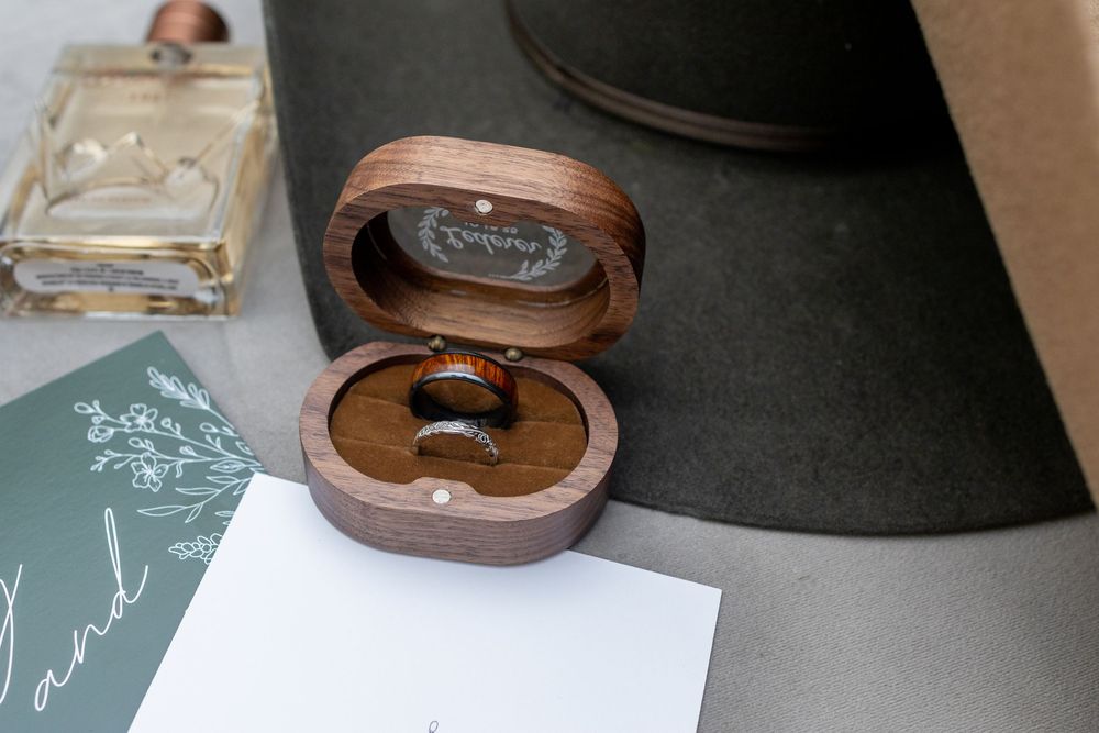 Wedding detail shots of wooden ring boxes and decor arranged on a table.