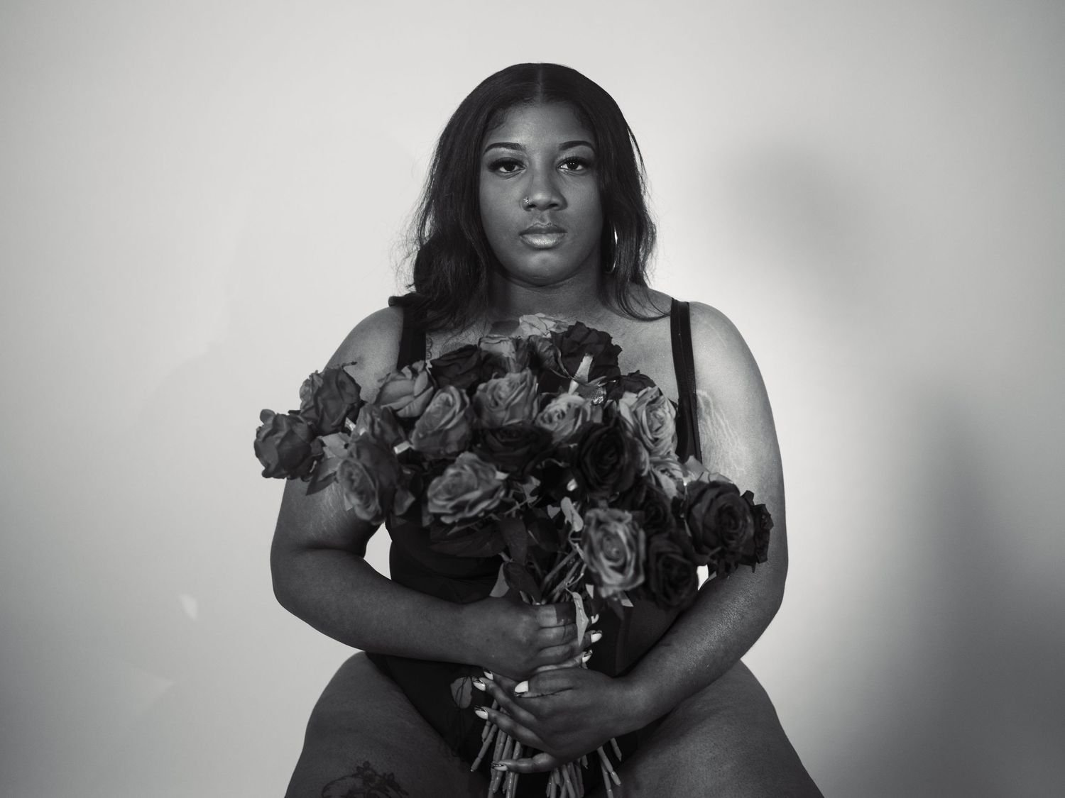 A black and white portrait featuring a dramatic bouquet of dark roses.
