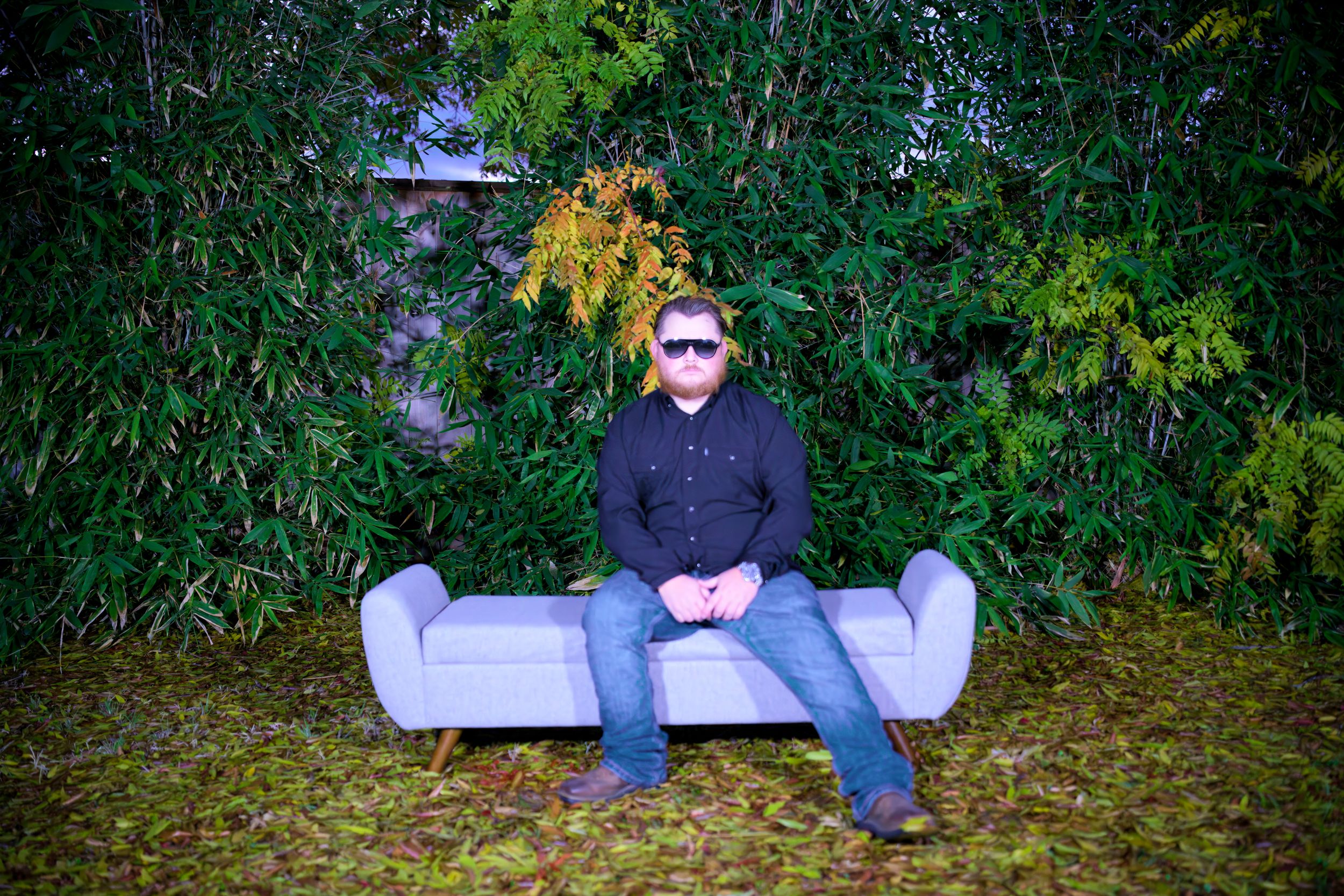 Person relaxing on ground surrounded by green foliage in outdoor setting.