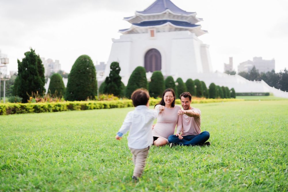 A toddler running toward his parents on the grass field of CKS Memorial Hall.