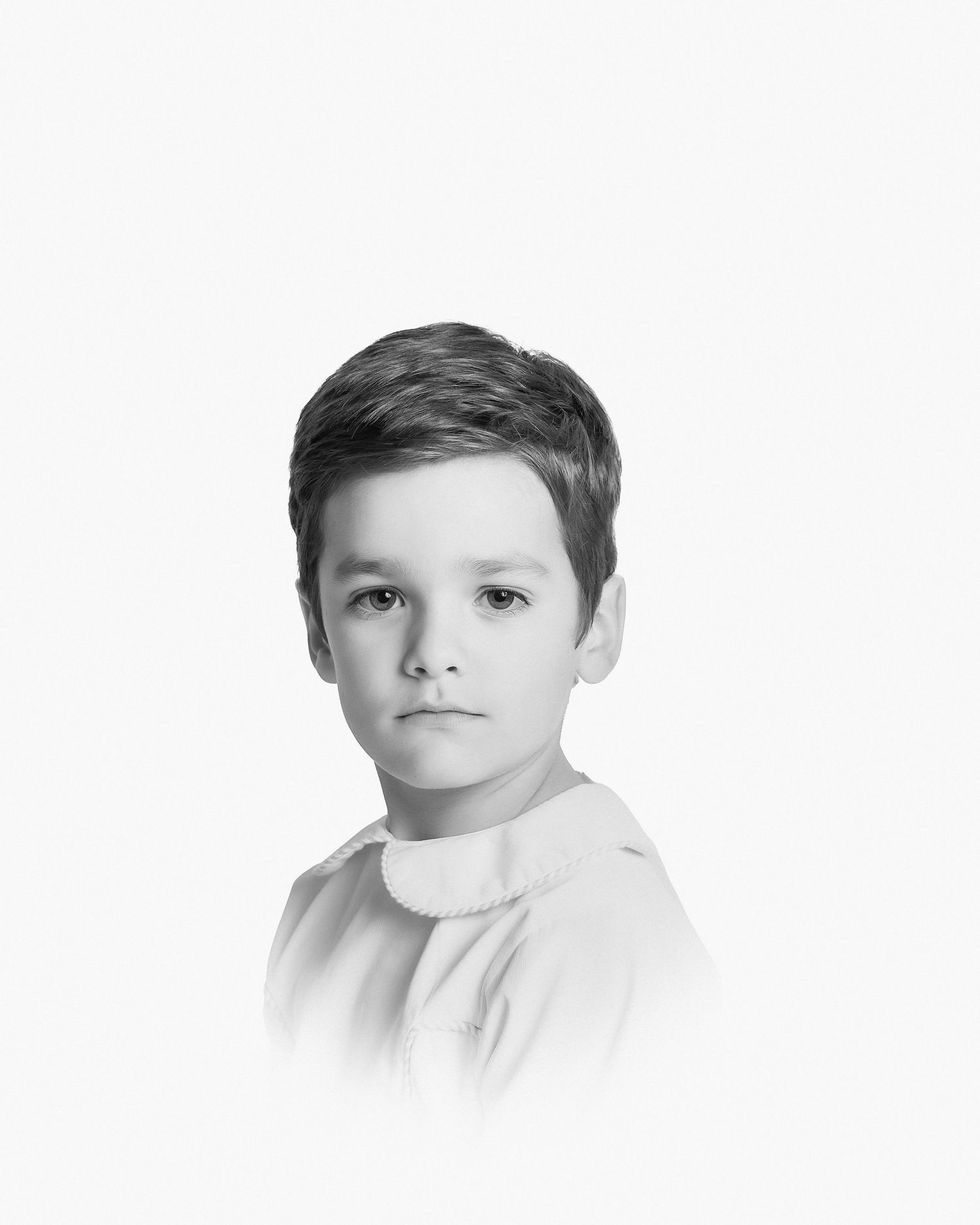 A classic black and white portrait of a young child wearing a light-colored shirt against a plain backdrop.