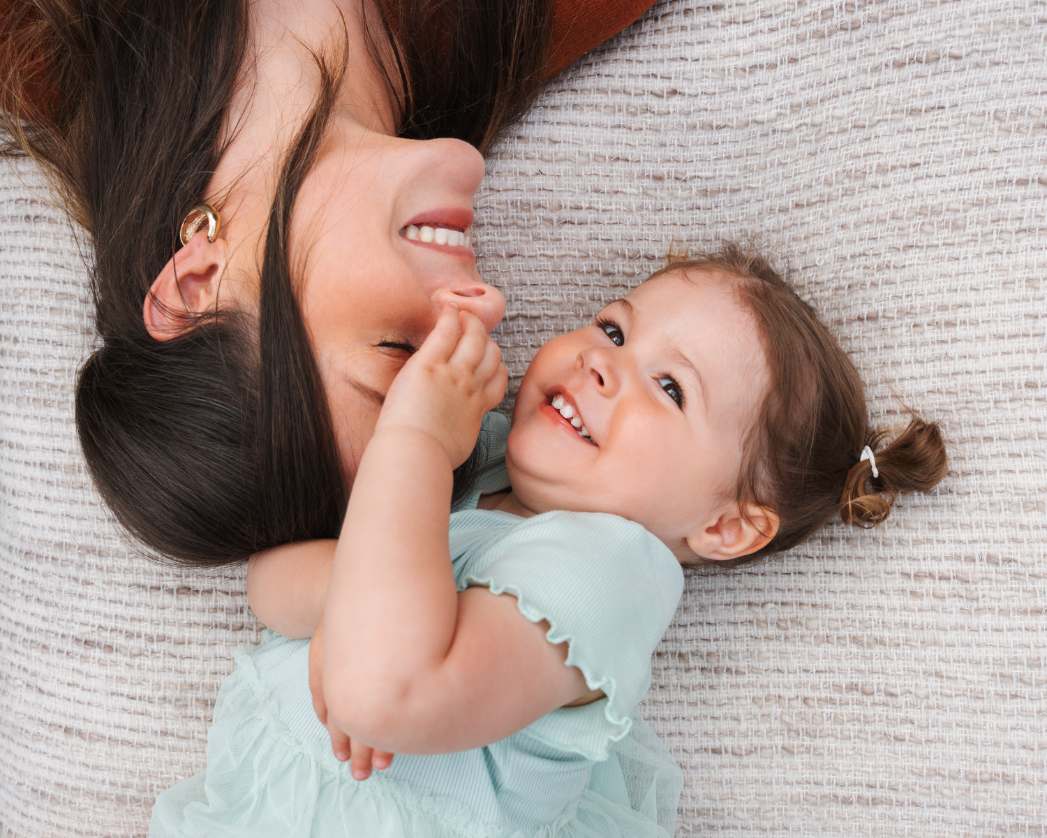 A candid moment of laughter and play captured on a white textured blanket.