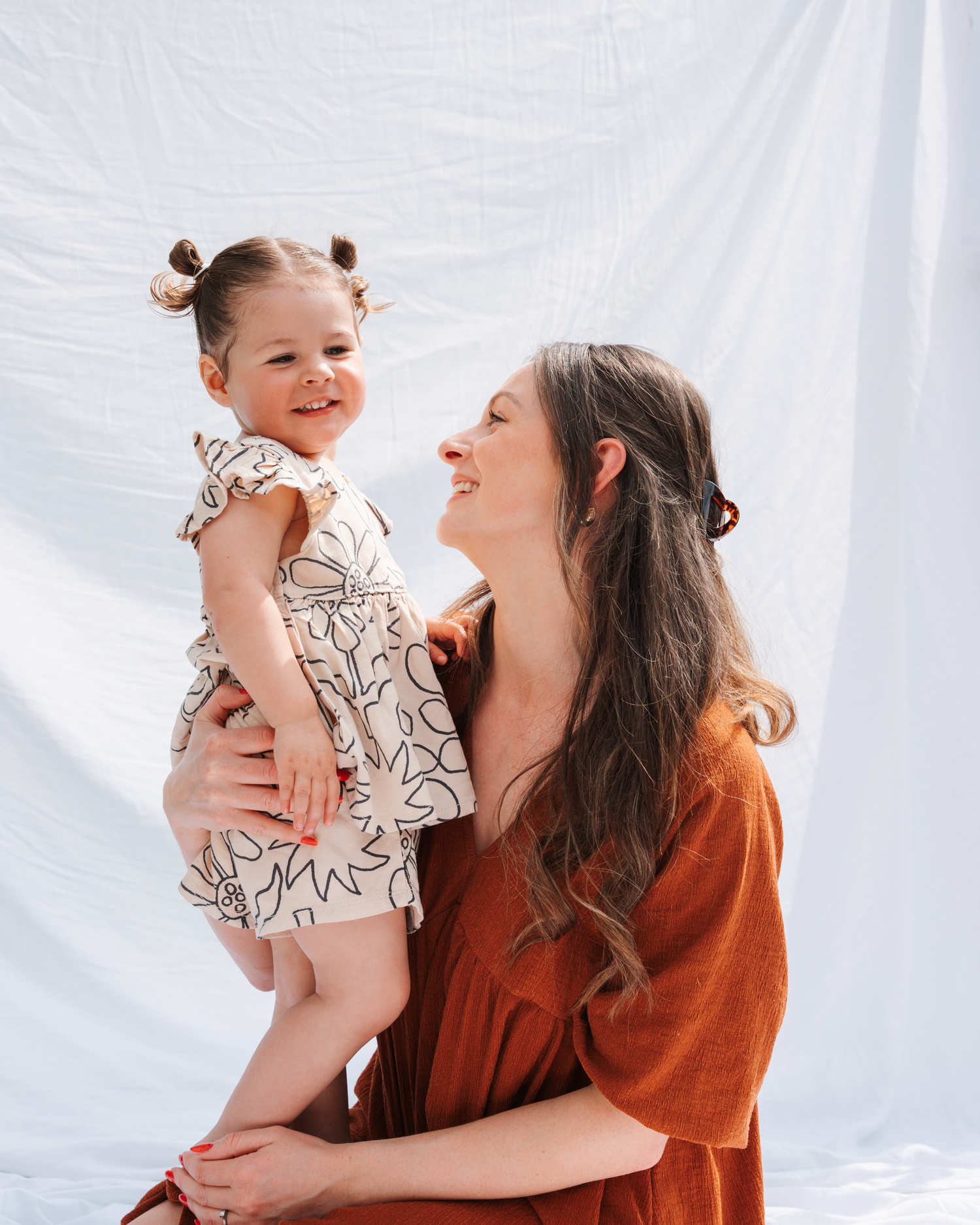 A joyful moment between parent and child against a white backdrop.