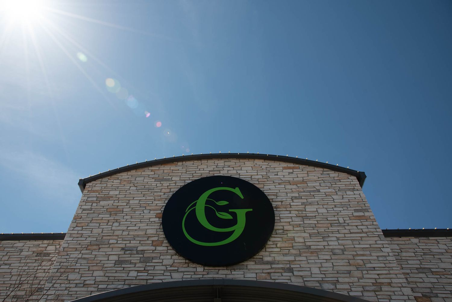 Storefront of Bradford Greenhouse in Barrie, ON with blue sky and sun in background