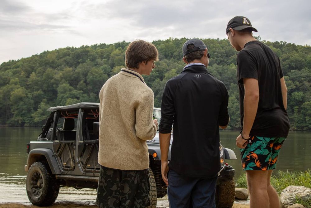 three men looking at Gray Jeep Wrangler offroad