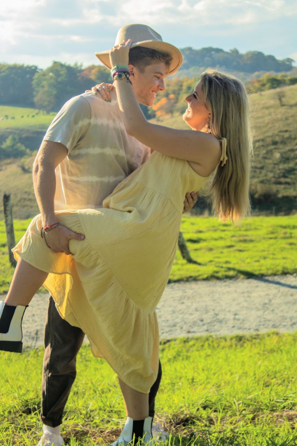 couple in mountains playing with large hat