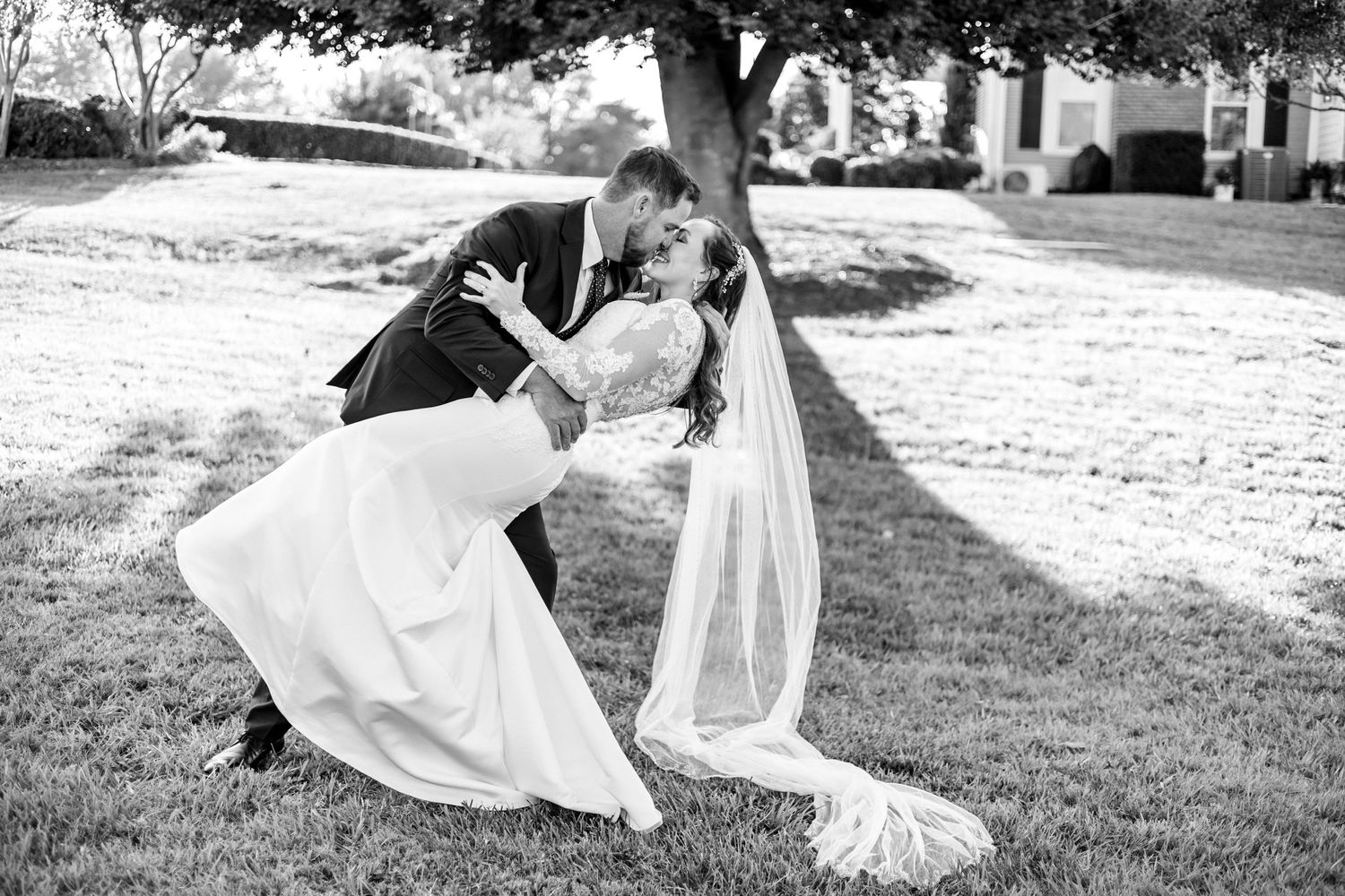Black and white photo of couple in romantic dip pose with flowing veil.