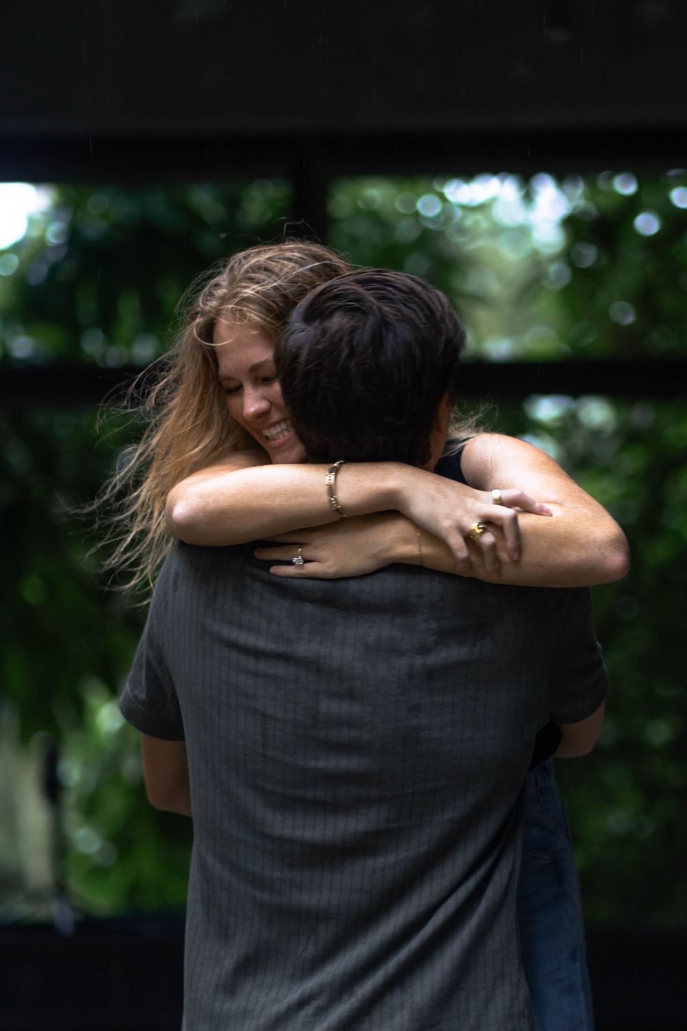 Intimate embrace captured in a lush green outdoor setting.