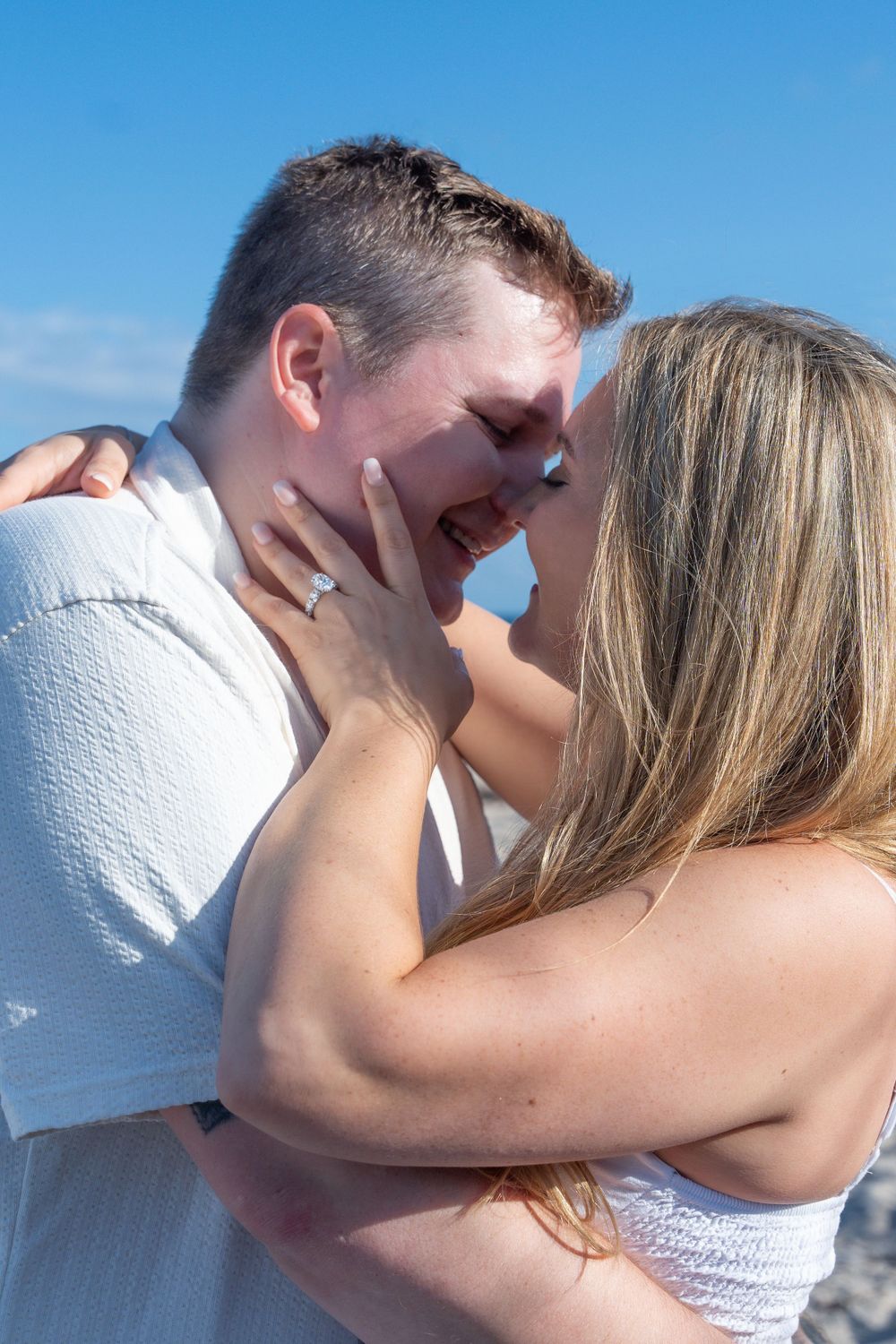 Intimate close-up of newly engaged couple sharing emotional moment on beach.