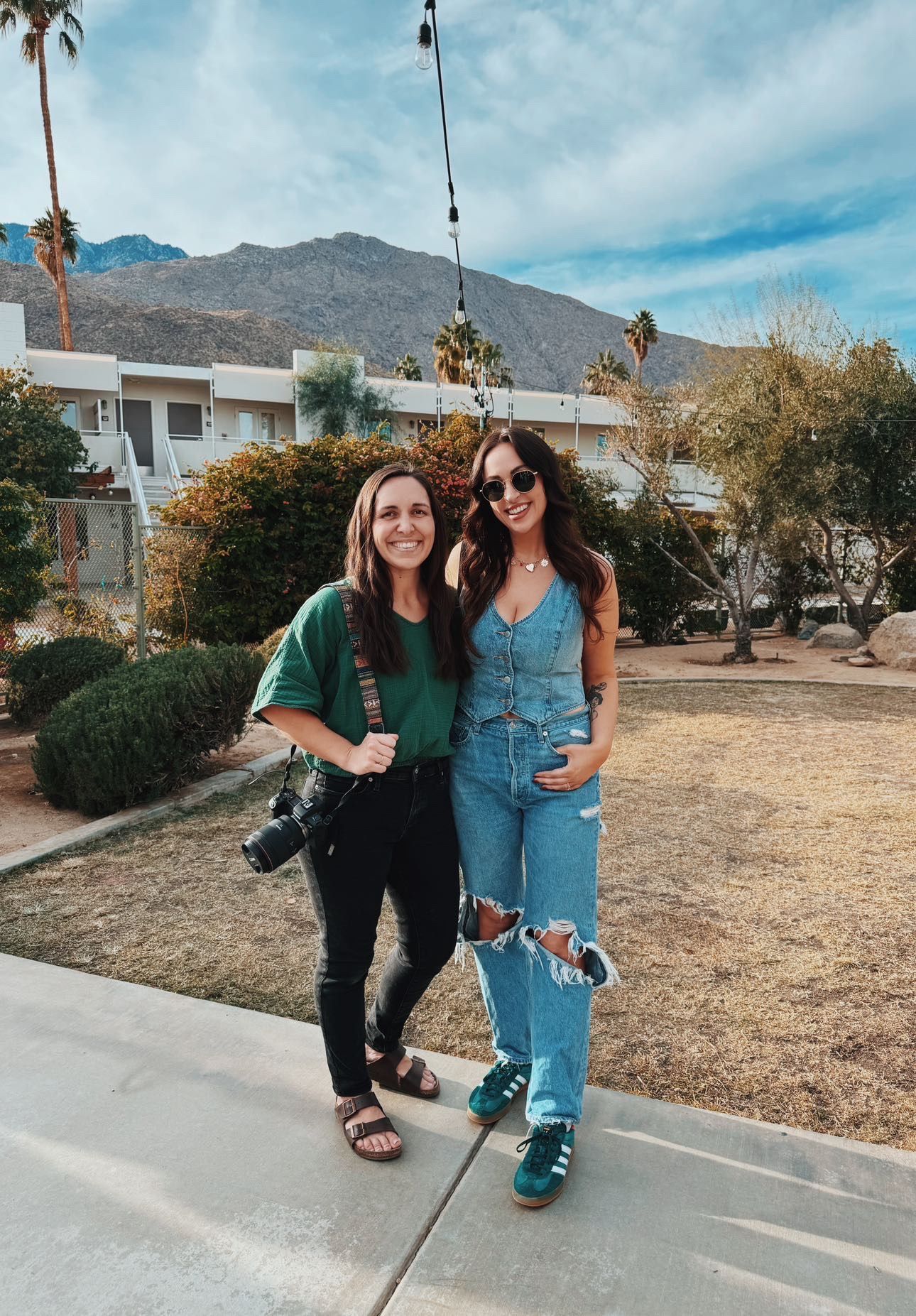 Two photographers standing together in casual attire against a desert mountain backdrop.