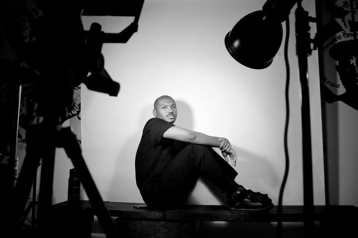 Black and white studio photography setup with lighting equipment and figure in silhouette.